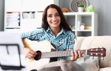 Kareli gömlek giyen güzel bir esmerin portresi. Harika bir kadın kameraya mutluluk ve gülümsemeyle bakıyor. Müzik konsepti. Bulanık arkaplan