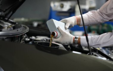 Beyaz eldivenli, otomatik mekanik erkek ellerine odaklan. Makine sıvısı kutusu kullan ve tam olarak spor arabanın kaputunun altına boşalt. Otomotiv denetimi kavramı
