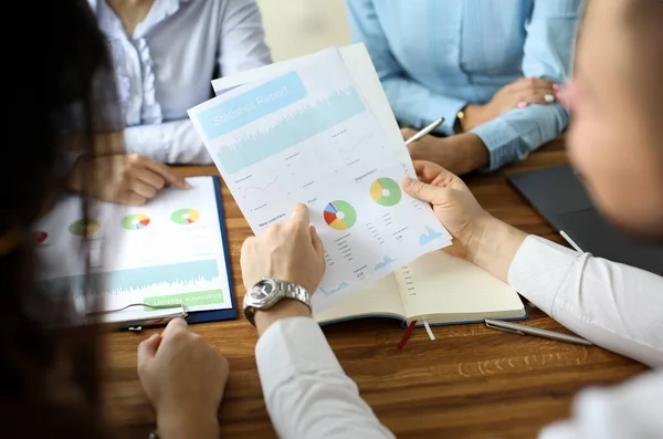 Close-up of financial statement in businessman hands. Biz team speaking about statistics report with graphs, charts, diagram. Business meeting and teamwork concept