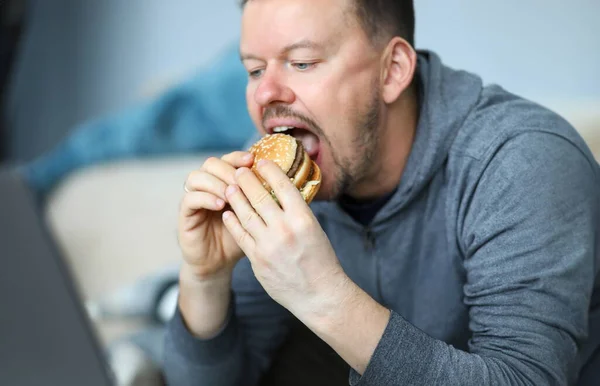 Portrait Male Sitting Indoors Eating Big Tasty Hamburger Full Mischievous — Stockfoto