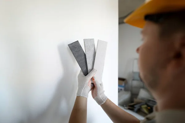 Male builder in white protective gloves hold gray ceramic tile in hands closeup. Design supervision of repair process concept
