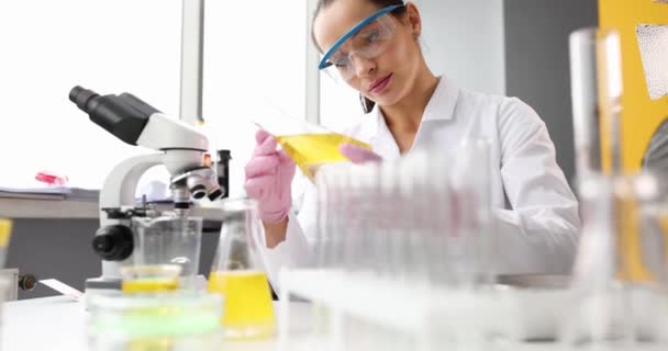 化学家科学家观察化学实验室密闭中带有黄色液体或油的瓶子的透明度 石油产品 燃料和润滑油的研究 — 图库视频影像