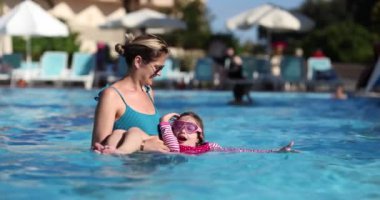 Mutlu çocuk yüzme havuzunda anne ve kızını eğlendiriyor. Yaz tatilleri ve rahatlama