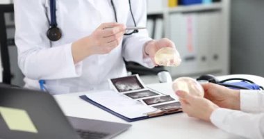 Plastik cerrah hastanın silikon göğüs implantlarını gösteriyor. Kadın doktorla konuşuyor, göğüs büyütme ameliyatına hazırlanıyor.