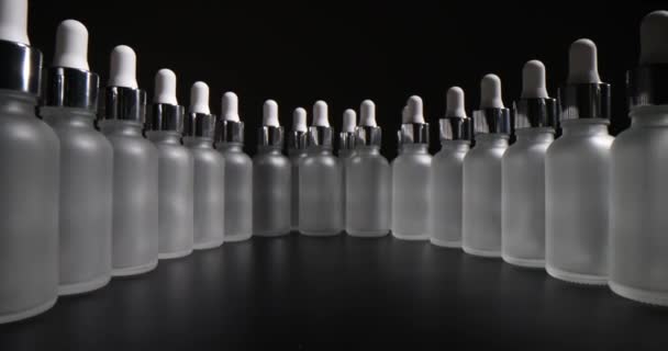 灰色の背景に空のガラス化粧品ボトルの列 皮膚科ラボでエッセンシャルオイルとフェイシャル血清のためのガラスウェア — ストック動画