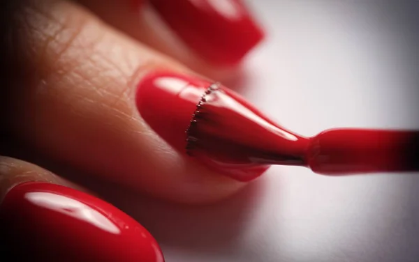 Manicurists apply red nail gel polish on finger. Manicure services and beautiful nails concept