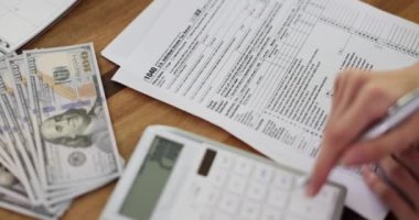 Kadın, burs başvuru formunu imzalayan banknotları sayıyor. Bayan, kişisel gelir vergisi iadesi anlaşmasına karşı hesap makinesindeki ödemeyi yavaş çekimde sayıyor