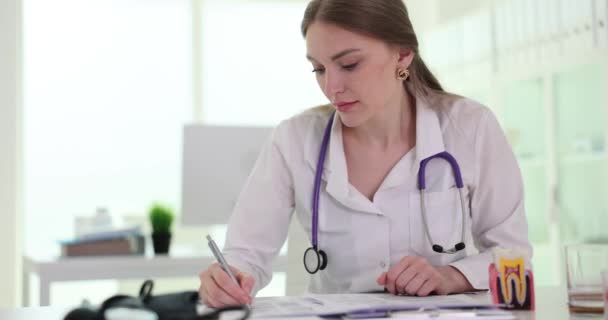 女性の専門医は 診療所で病気の患者に処方箋を書いています 検査室のスローモーションのドクター — ストック動画
