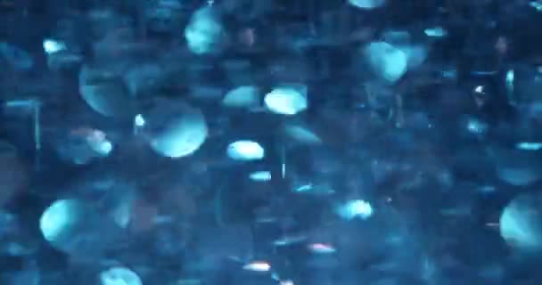 暗い背景に輝く青い光沢のある円の落下の断片 明るいホイルの菓子の装飾のお祝いとお祝いのパーティーの概念 — ストック動画