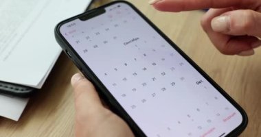 Kadın girişimci, önemli bir iş görüşmesi için cep telefonu seçme gününü kullanarak takvime göz atıyor. Zaman yönetimi kavramı