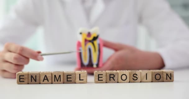 フレーズエナメル エロシオンは 歯の一部を示す女性の症候学者に対する小さな木製のブロックで構成されています エナメルとの歯の問題 — ストック動画