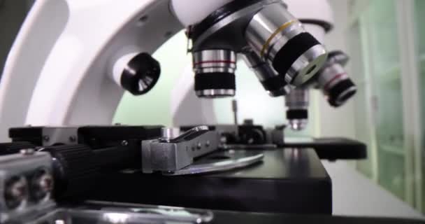 専門の診療所の実験室の研究のための顕微鏡 実験室の特別なテストのためのさまざまなレンズが付いている器械 — ストック動画