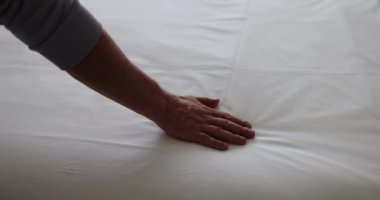 Otel odasındaki beyaz çarşaflara dokunan ziyaretçi eli. Turist otel odasındaki beyaz çarşaflara dokunmaktan hoşlanıyor.