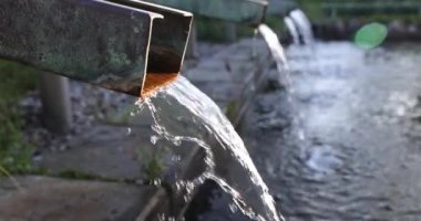 Halka açık çeşmedeki geniş borulardan akan su. Turistler ve ziyaretçiler için tatil beldesi şehir parkındaki güneş ışığı çeşmesi