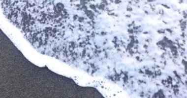 Parlak batan güneşin aydınlattığı kahverengi kumlara çizilmiş metin çağı. Yumuşak köpüklü dalgalar plaj temizleme kelimelerini silip süpürür.