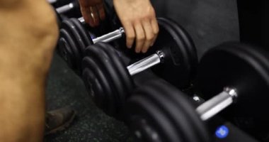 Adam spor salonunda dambıl eğitimi alıyor. Kas güçlendirme ve sağlık tanıtımı için spor merkezlerindeki eğitim ekipmanları yavaş çekim