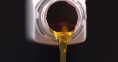 İşçi araba yağını plastik kutudan motor bölmesine boşaltıyor. Tamirci koyu arka planda araba tamir ediyor. Araba servisi kavramı