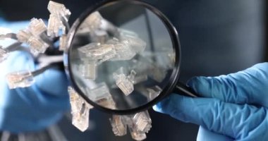 Lastik eldiven giyen bilim adamları büyüteçteki kablolara, karanlık öncül makroda bakıyor. Stüdyoda büyütülmüş boyuttaki nesneleri inceleme kavramı