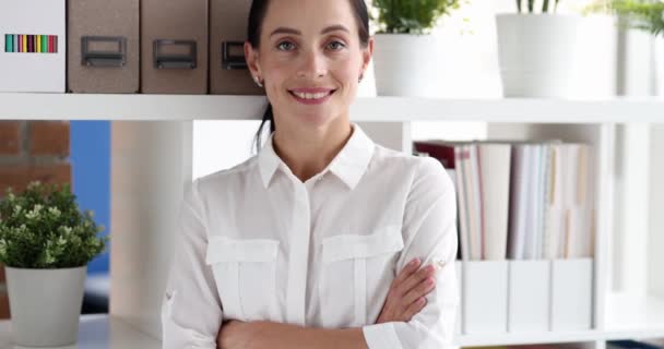 成功した女性起業家は会社のオフィスで交差した腕で微笑む 職場のスローモーションで棚にポーズする労働者の概念 — ストック動画