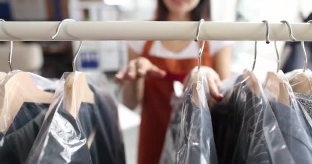 ドライクリーニング4K映画のハンガーにセロハンバッグで服をソート女性 衣料品修理サービスのコンセプト — ストック動画