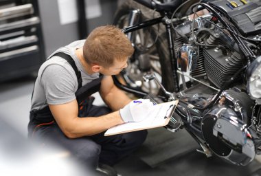 Servis onarım merkezindeki ustabaşı motorsiklet parçalarına teşhis koyuyor. Konsept motosikletlerin hizmet ve garanti hizmeti