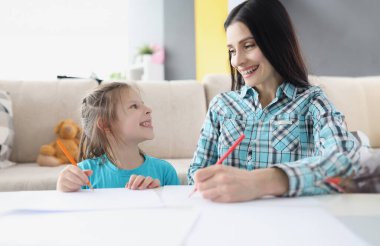 Mutlu anne ve kız kalemleri kâğıda çiziyor. Çocuk konseptinin yaratıcı yeteneklerinin geliştirilmesi