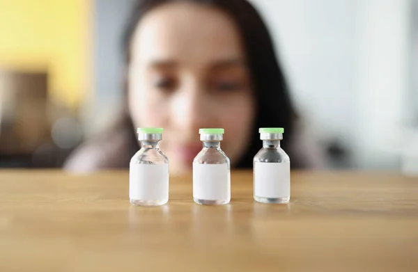 Woman looks at vaccine bottle and decides which one to choose. Comparison of coronavirus vaccines concept