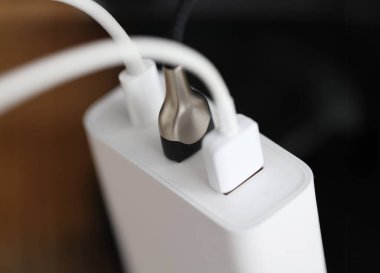 Beyaz USB kablosu prize takılıyor. Bilgisayarlar ve telefonlar şarj ediliyor