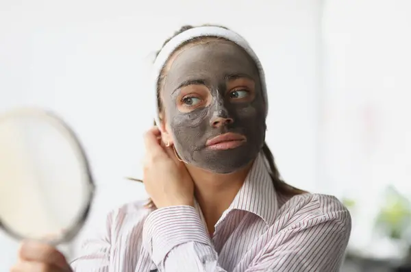 Young woman makes rejuvenating clay face mask. Facial skin care concept