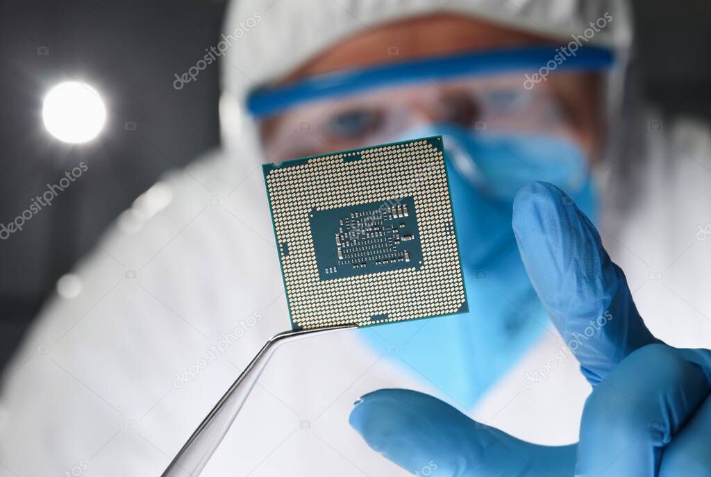 Researcher holds small microcircuit with tongs. Chipping and microcircuits concept