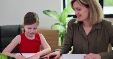 Anne, öğretmen ve kızı renkli kalemlerle kağıda resim çiziyor. Çizim eğitimi