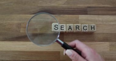 Büyüteç ve arama sözcüğü tahta arka planda küp üzerine yazılmış. Arama motoru optimizasyon kavramı