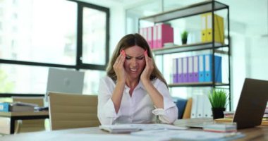 Yorgun, stresli bir iş kadını iş yerinde güçlü bir baş ağrısı ve masaj hissediyor. Ofiste baş ağrısı ya da kronik migrenden muzdarip kadın çalışan.