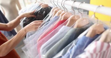 Kadın terzi atölye filminde plastik poşetlerle elbise asıyor. Kuru temizleme hizmeti konsepti