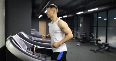 Koşu bandında koşan ve spor salonunda kardiyo antrenmanı yapan bir sporcu. Spor kulübünde antrenman yapan fitness adamı.