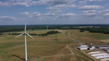 Tarlaların ve ormanların arka planına karşı elektrik türbinleri. Yenilenebilir ve çevre dostu enerji kavramı. 4k video filmi
