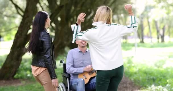 Ανάπηρος Παίζει Κιθάρα Στο Πάρκο Δύο Γυναίκες Χορεύουν Ομάδα Υποστήριξης — Αρχείο Βίντεο