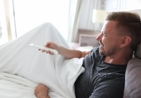Glimlachende Man Ligt Bed Drukt Knoppen Afstandsbediening Concept — Stockfoto