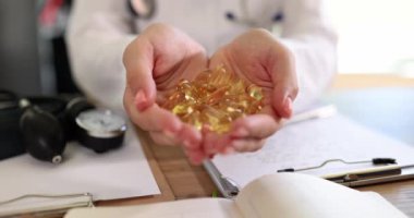 Doktor, klinikte elinde bir sürü Omega 3 kapsülü tutuyor. 4K 'lık filmi yavaş çekimde çekiyor. Beslenme takviyesi kavramı ile tedavi