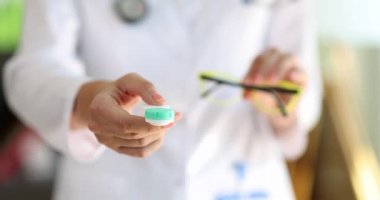 Doctor ophthalmologist holding eyeglasses and contact lenses in hands closeup 4k movie slow motion. Vision correction concept