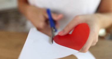 Woman cutting out of paper red heart with scissors closeup 4k movie slow motion. Valentine day cards concept