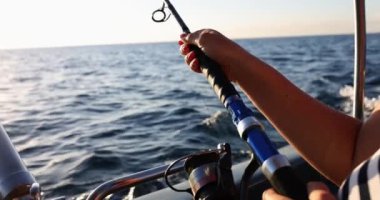 Fisherman sailing on boat and catching fish with fishing rod closeup 4k movie slow motion. Hobby fishing concept