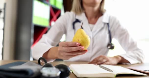 Doctor Nutritionist Holding Out Pear Fruit Clinic Closeup Movie Slow — Stockvideo
