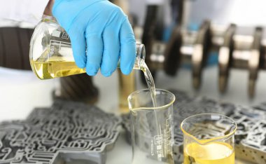 Motor yağı otomatik vites ve hidrolik yükseltici kimya test tüp elinde üretir koruyucu eldiven erkek el ele tutuşur