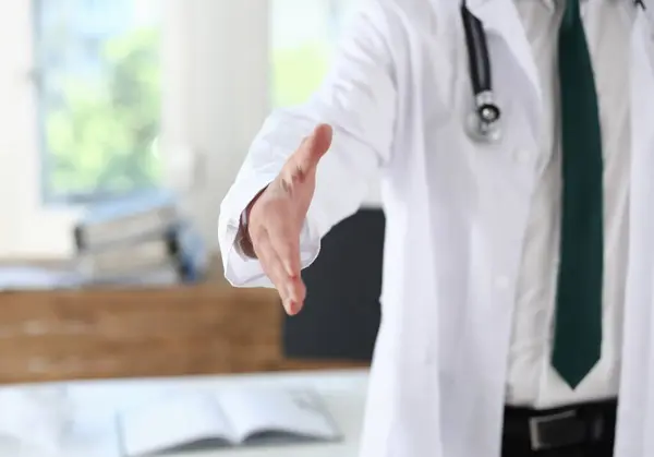 Male medicine doctor offering hand to shake in office closeup. Greeting and welcoming friend introduction or thanks gesture. Tests advertisement concept. Physician ready to examine patient