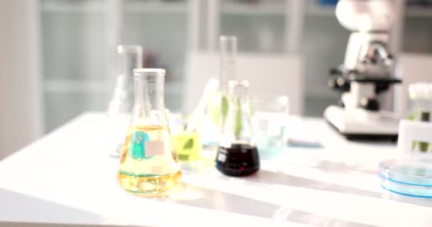 製薬実験室のテーブルの上に黄色と黒の液体が付いているガラス試験管およびフラスコ 石油製品の化学組成を研究する — ストック動画