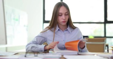 Stajyer öğrenci yöneticisinin ofisteki iş yerindeki günlük sayfalarına bakması. Sinir yöneticisinin elinde dokümanları olan büyük dizin ya da dizin