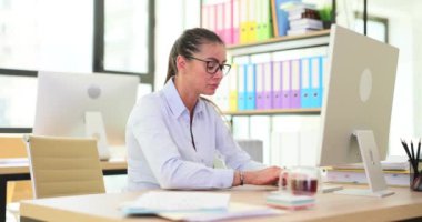 Düşünceli kadın masada oturup düşünüyor, çalışıyor ya da ofiste bilgisayar başında çalışıyor. Klavyede yazan düşünceli yönetici stajyeri