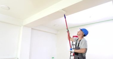 Adam tavanı kapalı mekanda beyaz boyayla boyuyor. Boyama duvarları ve tavan beyazı