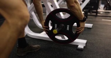 Spor salonunda ağırlık kaldırma halterinden ağırlık plakalarını çıkarıyorum. Güç antrenmanı ve halter ağırlık seçimi